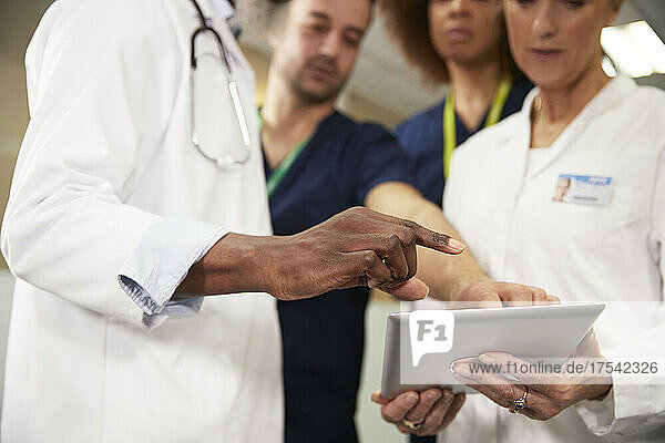 Doctor gesturing near colleagues using tablet PC in meeting at hospital
