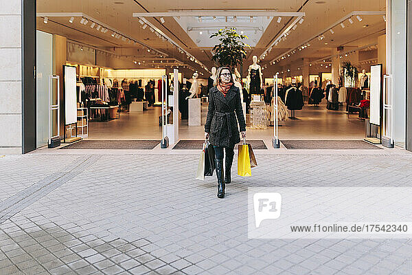 Woman with shopping bags walking out of clothing store