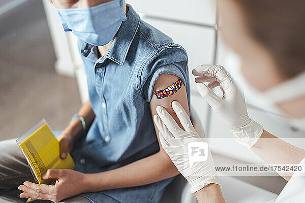 Healthcare worker putting adhesive note on vaccinated boy's arm at center