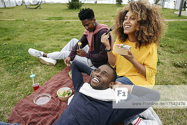 Woman eating lunch with friends in park at picnic
