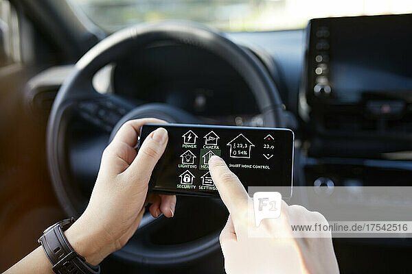 Businesswoman controlling smart house through mobile phone while sitting in car