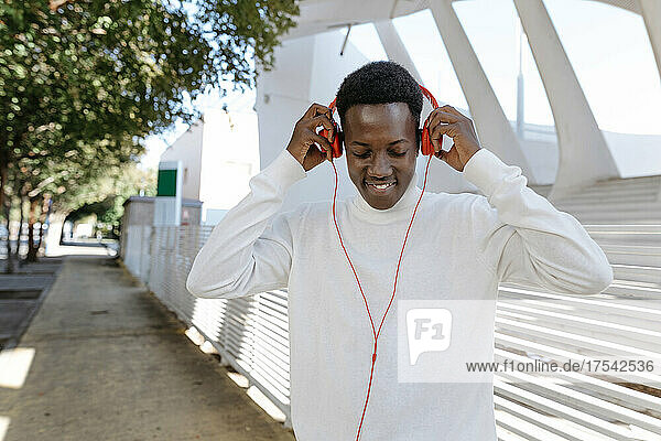 Smiling man wearing headphones on footpath