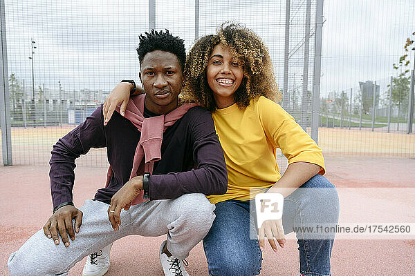 Young woman with arm around friend at sports field