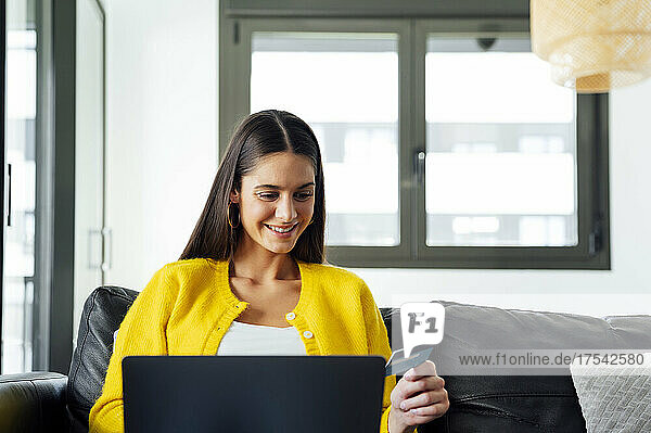 Smiling woman with credit card doing online shopping on laptop