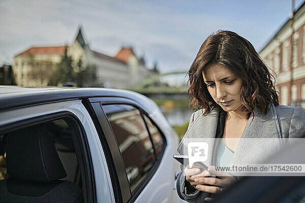 Frau nutzt Mobiltelefon im Elektroauto