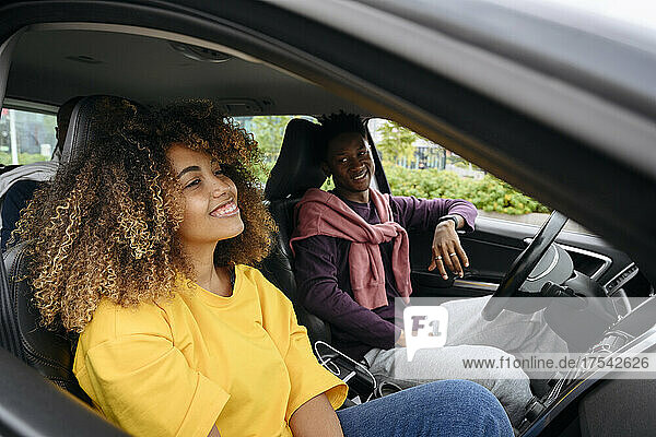 Lächelnder Mann blickt Freund an  der im Auto sitzt