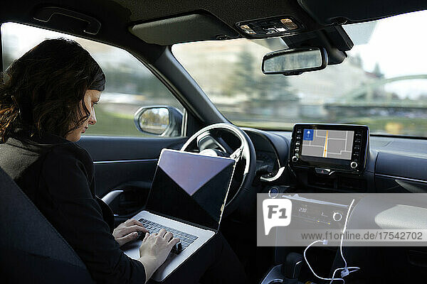 Businesswoman with laptop working in driverless car