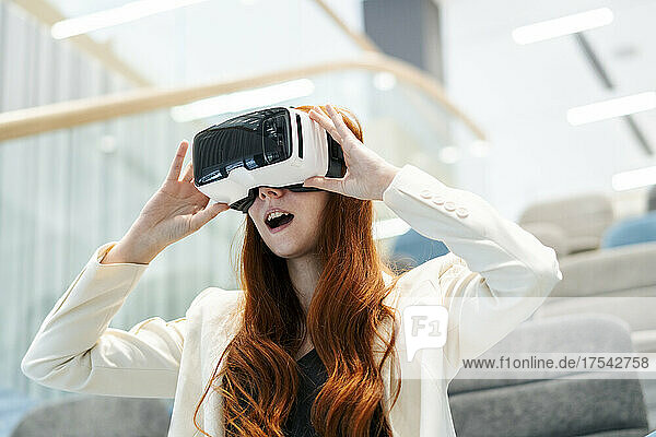 Businesswoman with mouth open looking through virtual reality simulator in office