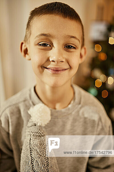 Cute boy smiling in front of christmas tree at home