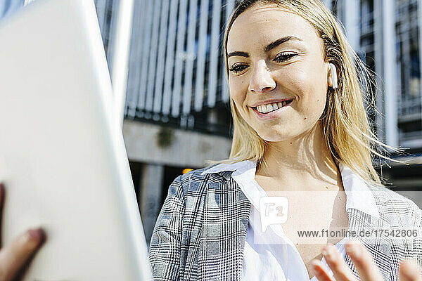 Smiling young businesswoman on video call through tablet PC