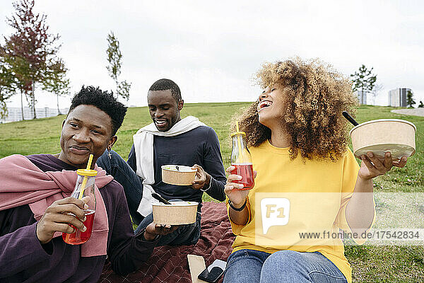 Woman laughing and having juice with friends at picnic