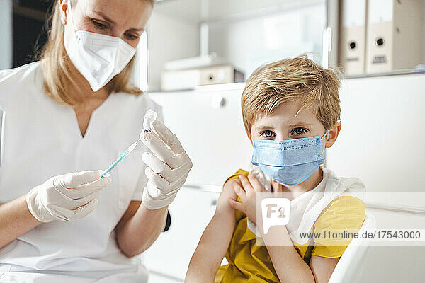 Boy with protective face mask getting vaccinated at center