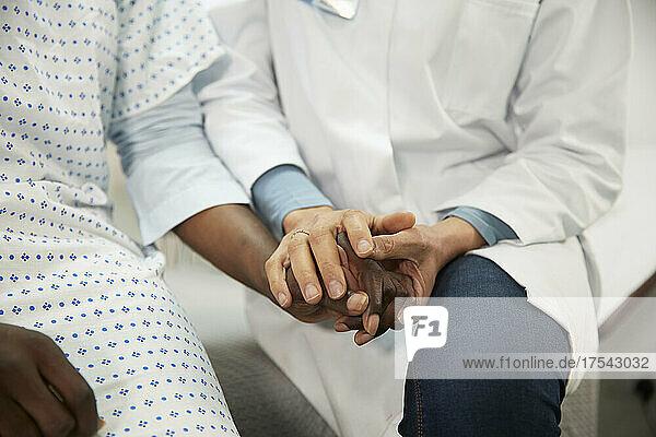 Arzt hält Händchen des Patienten im Krankenzimmer