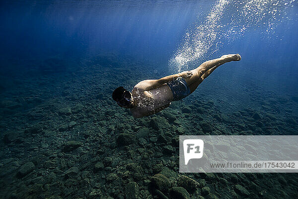 Young man with goggles swimming undersea