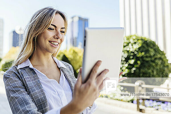 Smiling blond businesswoman on video call through tablet PC