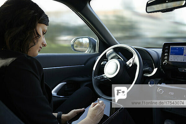 Businesswoman using tablet PC in driverless car