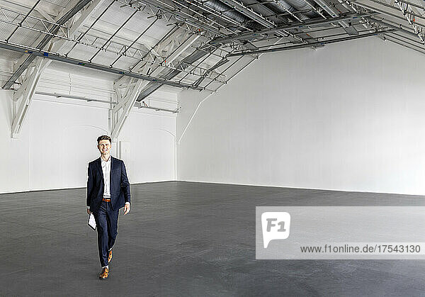 Young businessman walking in industial hall