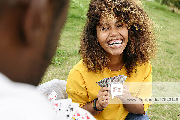 Woman laughing and playing cards with friend in park
