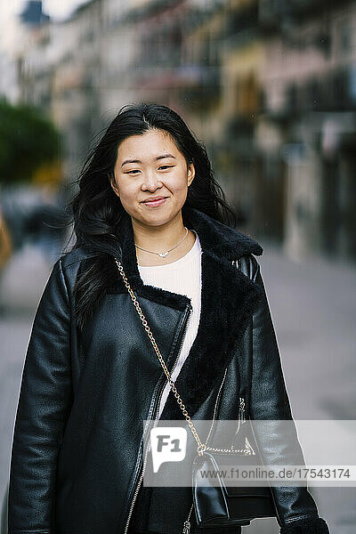 Young smiling woman wearing crossbody bag over black jacket