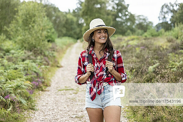 Smiling woman with hat walking on footpath at Cannock Chase
