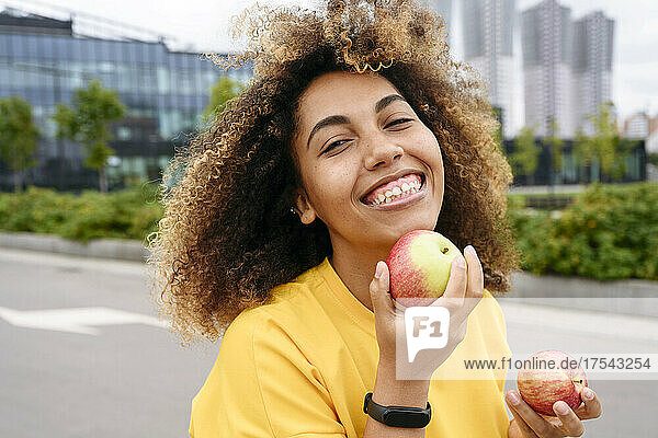 Smiling woman with apples on street