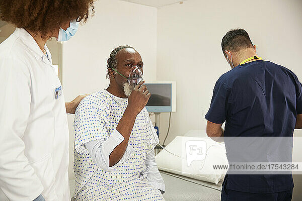 Female doctor talking to patient wearing oxygen mask in medical room