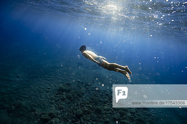 Shirtless young man swimming undersea