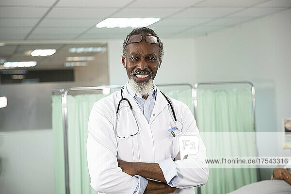 Confident male doctor with arms crossed in medical room