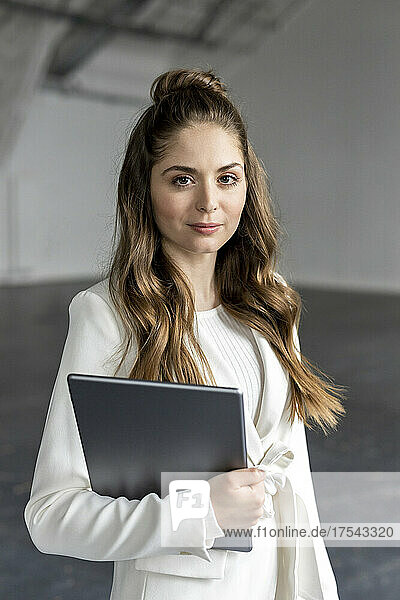 Young businesswoman holding tablet PC in industial hall