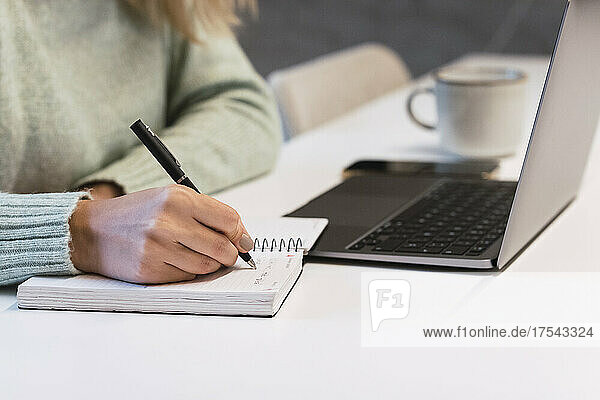 Businesswoman writing in diary at desk in studio