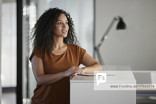 Businesswoman with tablet PC day dreaming in office
