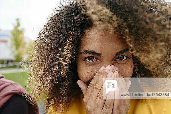 Young woman sneezing in hands
