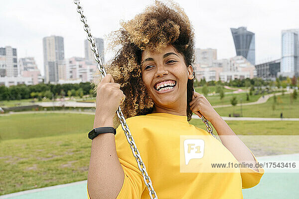 Happy woman playing on swing in park