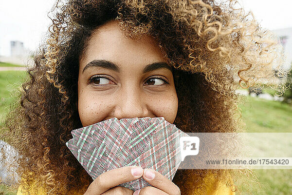 Young woman covering mouth with playing cards
