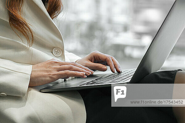 Hands of working woman typing on laptop in office