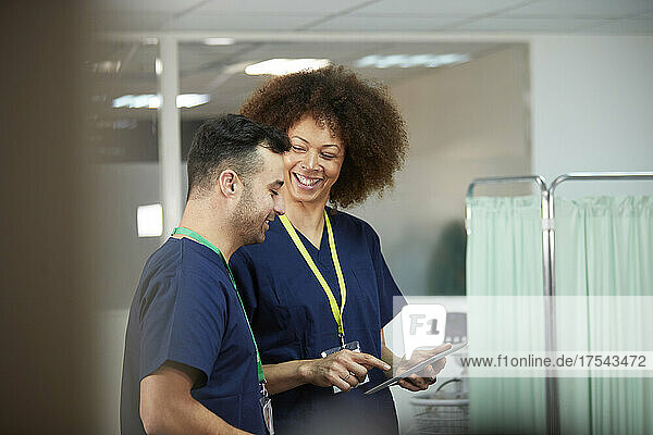 Smiling nurse with tablet PC looking at colleague in medical room