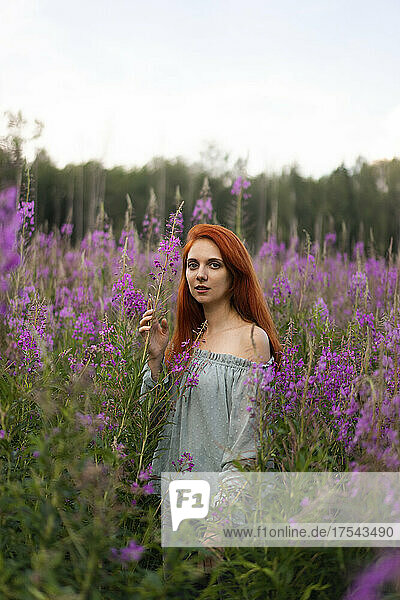 Redhead woman amidst pink flowers in field