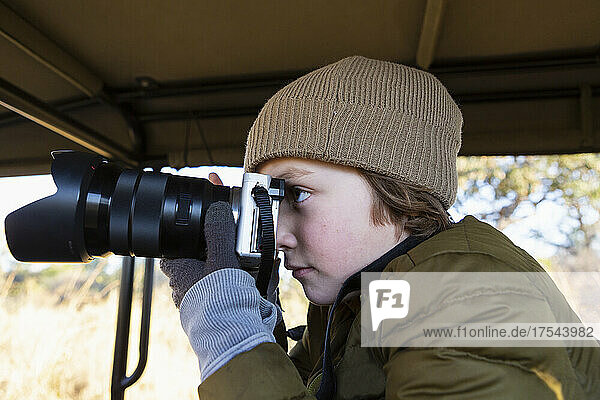 Eight year old boy with a camera in a safari jeep.