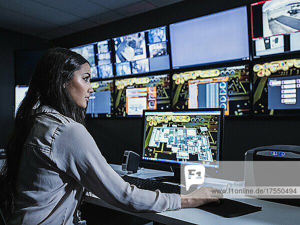 Mixed race security guard watching monitors in control room