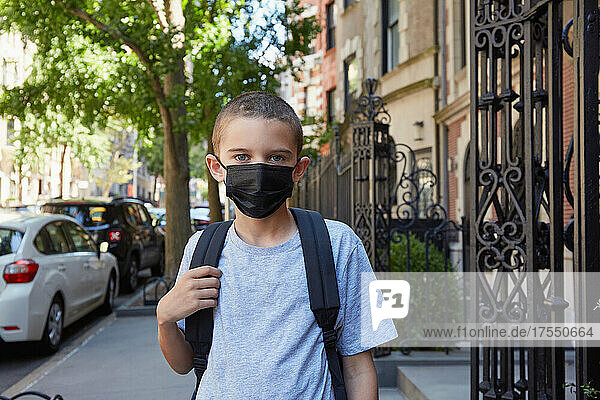 USA  New York  New York City  Portrait of boy (8-9) in face mask standing on sidewalk