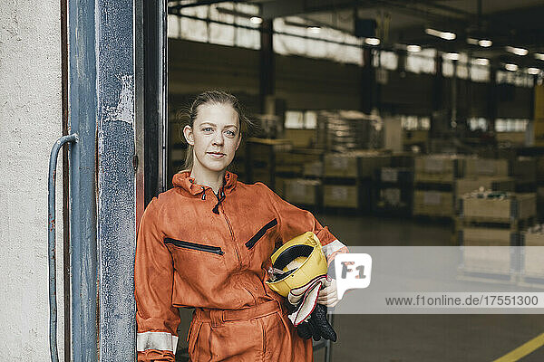 Porträt einer weiblichen Arbeiterin in Uniform  die am Eingang einer Fabrik steht