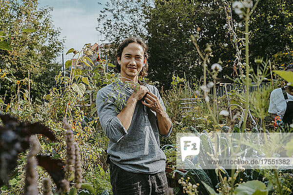 Porträt eines lächelnden männlichen landwirtschaftlichen Aktionärs mit Pflanze im städtischen Garten