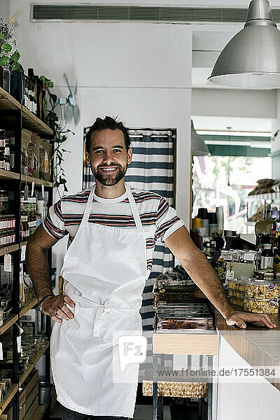 Portrait of smiling male entrepreneur with hand on hip in bakery
