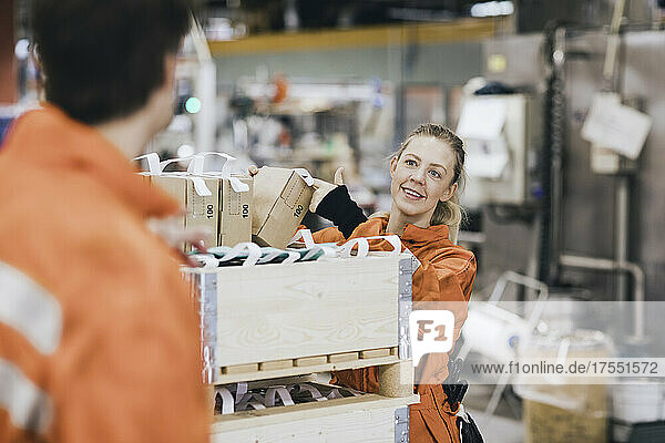 Smiling female worker talking with male coworker while working in warehouse