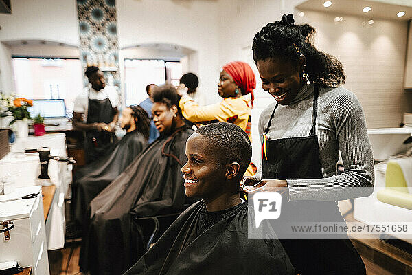 Lächelnde Friseurin beim Frisieren eines männlichen Kunden im Salon