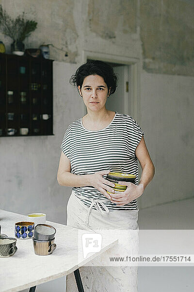 Porträt einer Unternehmerin mit Geschirr in einer Keramikwerkstatt