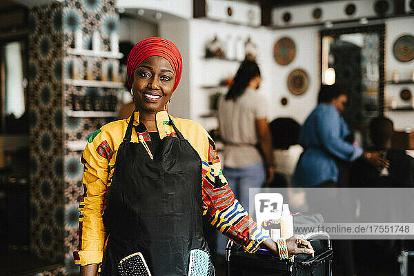 Portrait of confident female hairdresser with headscarf in barber shop