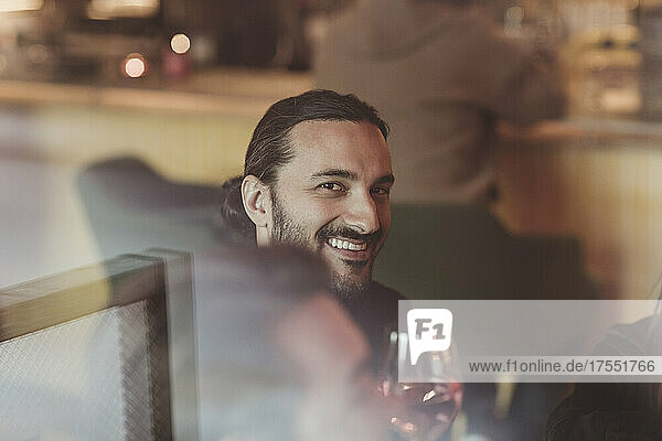 Porträt eines lächelnden Mannes mit Weinglas in einer Bar