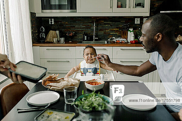Vater füttert kleinen Jungen am Esstisch in der Küche