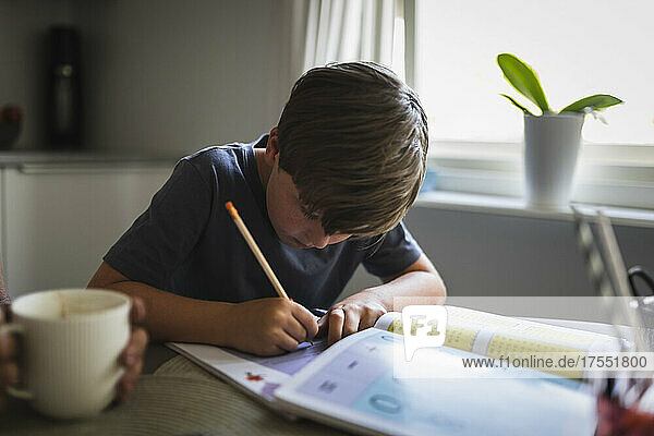 Junge schreibt beim Lernen zu Hause in ein Buch